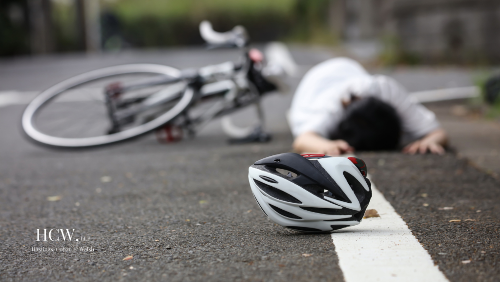 Injured bicyclist lying on roadway near bicycle helmet after a Connecticut bicycle accident involving potential driver negligence
